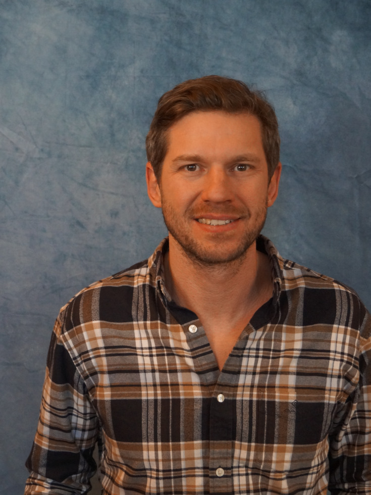 Smiling young man in plaid shirt.