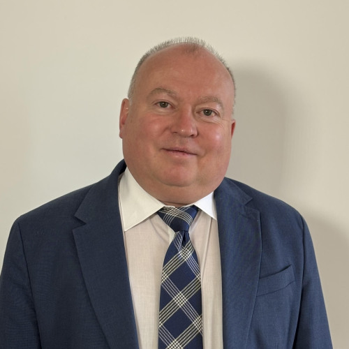 Older man in a blue suit and plaid tie.