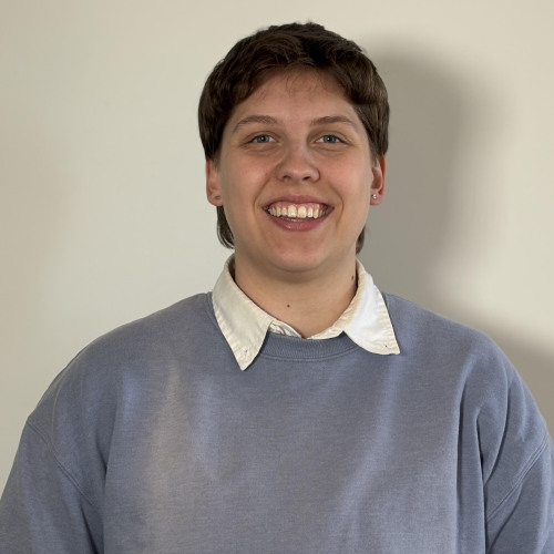 Woman with short hair in a blue sweater and white shirt.
