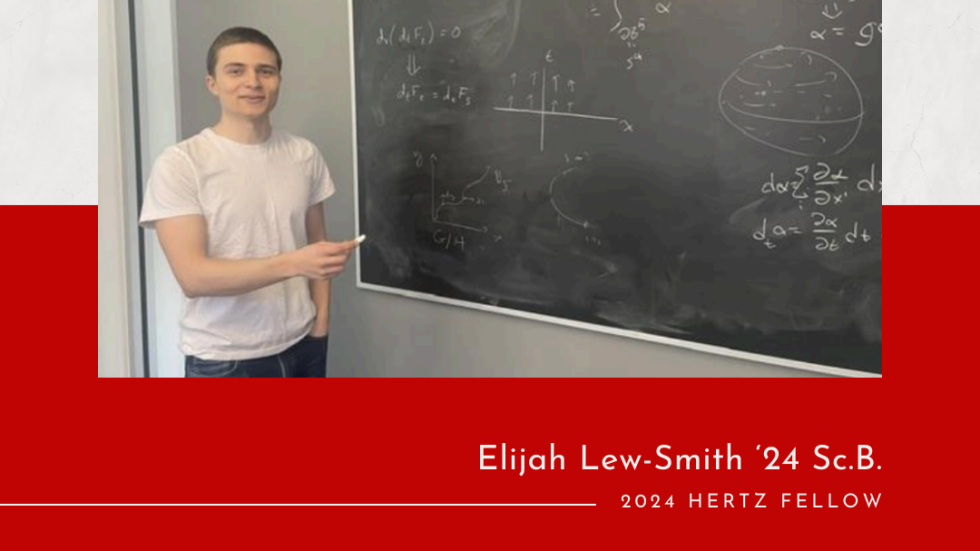 elijah Lew-smith standing in front of a blackboard holding chalk, equations on the board.