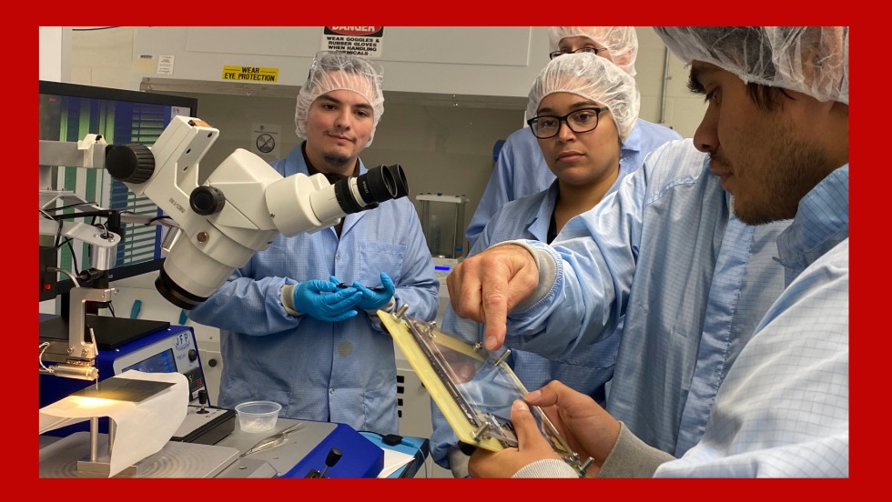 Philipp Wagenknecht (left), Yarelis Acevedo (center) and Nick Hinton (back) show Juan a device in the clean room.